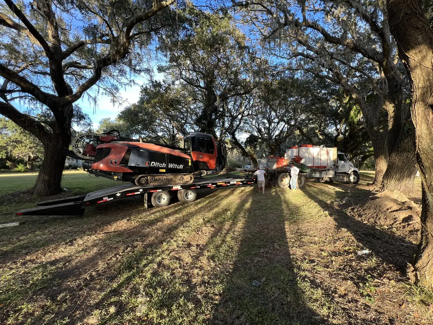 Ditch Witch AT40 bajando del tráiler bajo robles